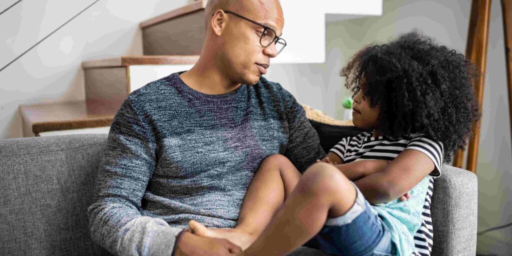 Parent and child talk on their living room couch.